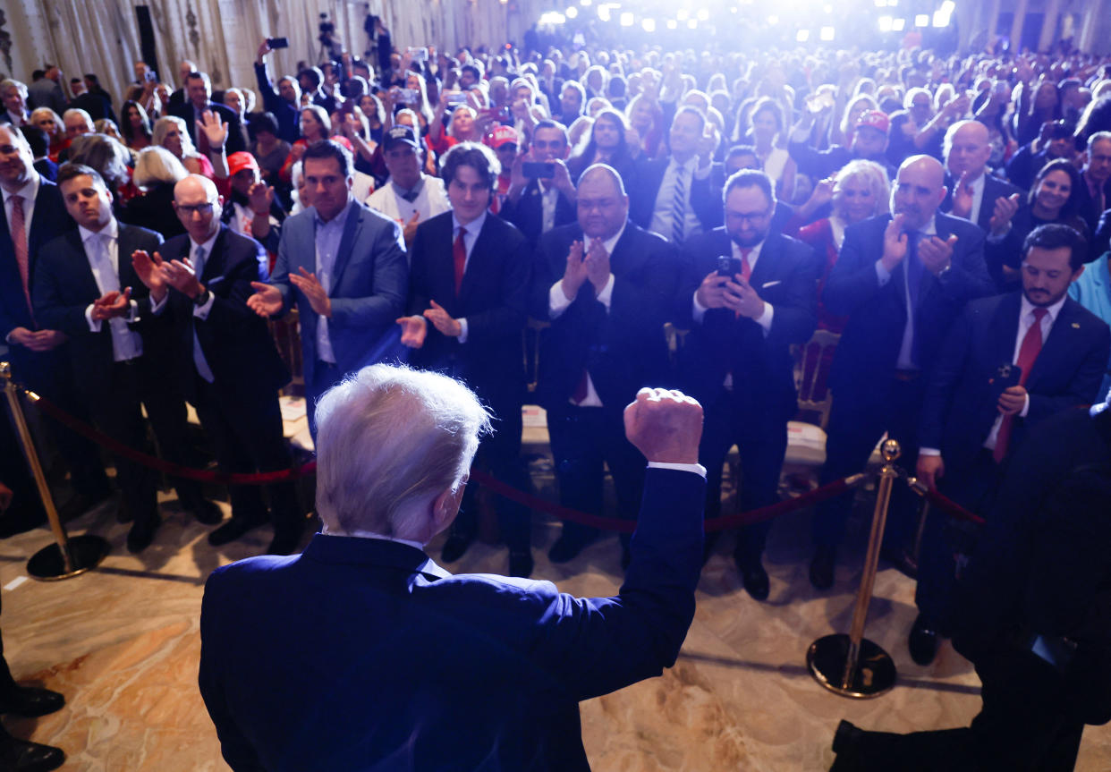 Former U.S. President Donald Trump thrusts his fist in the air in front of a large crowd of his family, associates and supporters.