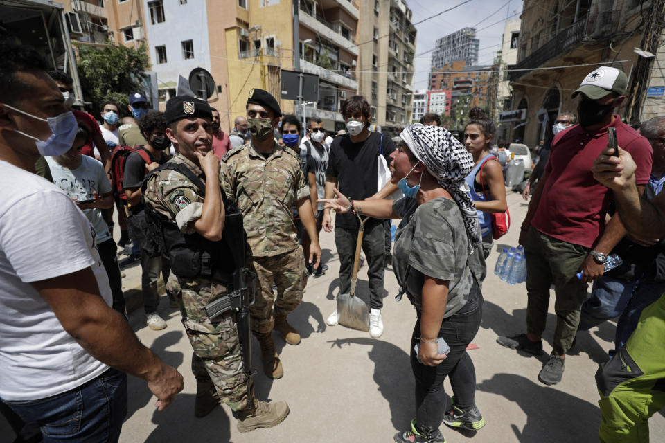 A woman yells at Lebanese soldiers as French President Emmanuel Macron visits the Gemmayzeh neighborhood, which suffered extensive damage from the Tuesday explosion at the seaport, in Beirut, Lebanon, Thursday, Aug. 6, 2020. Lebanese officials targeted in the investigation of the massive blast that tore through Beirut sought to shift blame for the presence of explosives at the city's port, and the visiting French president warned that without serious reforms the country would "continue to sink." (AP Photo/Hassan Ammar)