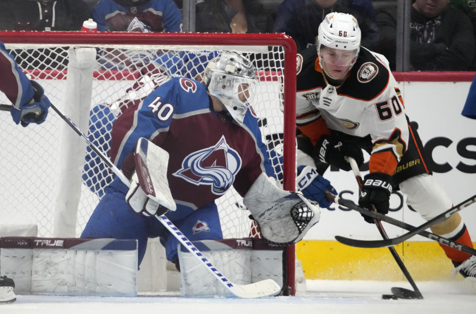 Anaheim Ducks defenseman Jackson LaCombe, right, puts the puck on Colorado Avalanche goaltender Alexandar Georgiev during the first period of an NHL hockey game Tuesday, Dec. 5, 2023, in Denver. (AP Photo/David Zalubowski)