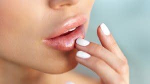 Lip Protection. Closeup of Beautiful Young Woman Healthy Lips. Female Model Mouth With Smooth Perfect Skin And Natural Manicure Touching Her Plush Lips. Lip Care And Beauty. High Resolution