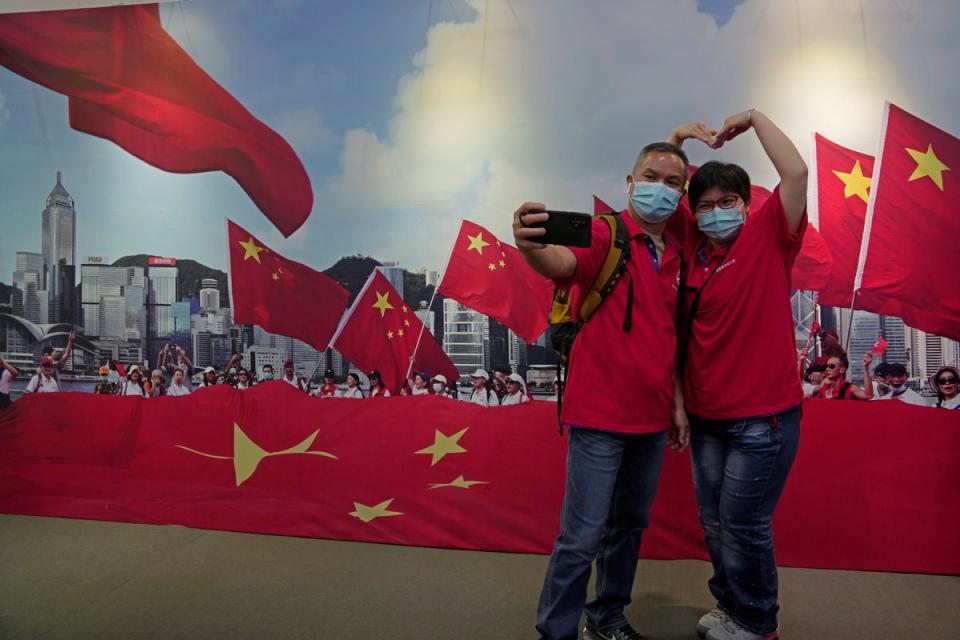 A couple pose in front of a banner featuring Chinese flags at an exhibition to mark the 25th anniversary of the former British colony’s return to Chinese rule, in Hong Kong on 24 June (AP)