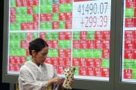 A person in traditional Japanese "kimono" walks in front of an electronic stock board showing Japan's Nikkei index at a securities firm Tuesday, July 16, 2024, in Tokyo. (AP Photo/Eugene Hoshiko)