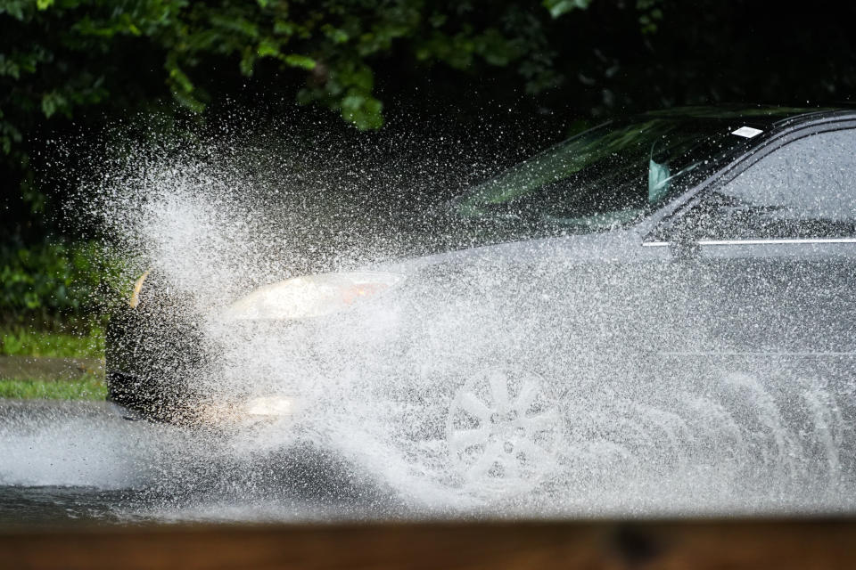 A car rides through flood waters that fill a roadway around Nancy Creek near Atlanta, as Tropical Storm Fred makes its way through north and central Georgia on Tuesday, Aug. 17, 2021. (AP Photo/Brynn Anderson)