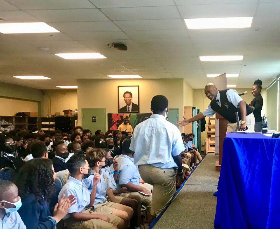 Thomas Cole, founder of Emma Jewel Charter Academy, high fives a winning scholar at a ceremony honoring students who won an essay contest designed to help them prepare for the Florida Standards Assessment.