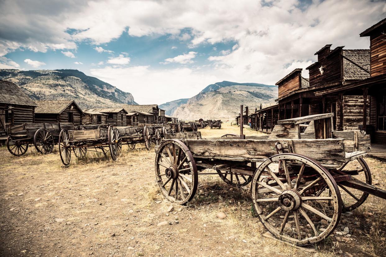 Old Trail Town, Wyoming, a ghost town, several old stagecoaches in the foreground, old western buildings on both sides, mountains in the background
