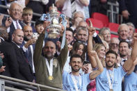 Manchester City's head coach Pep Guardiola, , left, holds up the winners trophy as he celebrates with team after winning the English FA Cup final soccer match between Manchester City and Manchester United at Wembley Stadium in London, Saturday, June 3, 2023. Manchester City won 2-1. (AP Photo/Dave Thompson)