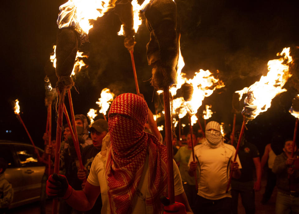 Palestinian demonstrators march with torches during a demonstration against the West Bank Jewish settlement outpost of Eviatar that was rapidly established last month, at the Palestinian village of Beita, near the West Bank city of Nablus, Sunday, June 27, 2021. The Palestinians say it was established on their farmland and fear it will grow and merge with other large settlements in the area. (AP Photo/Majdi Mohammed)