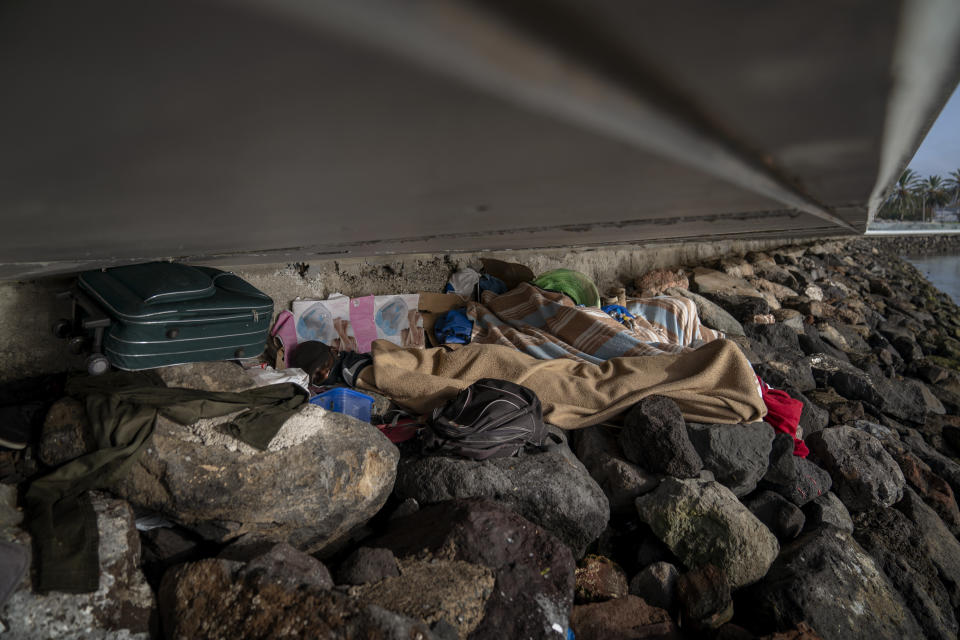 Khalid, a migrant from Gambia, sleeps on a breakwater under a bridge in Gran Canaria island, Spain, on Saturday, Aug. 22, 2020. The striking shift in migration back to the Canary Islands has raised alarms at the highest levels of the Spanish government. (AP Photo/Emilio Morenatti)