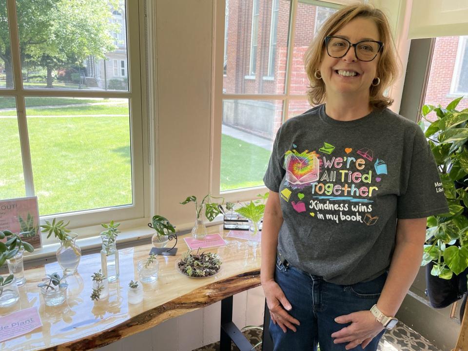 Dorsch Memorial Branch staff member Aimee Luck is shown by the library's houseplant collection. Luck started Dorsch's plant collection this summer and built this table with her husband to house the offerings.