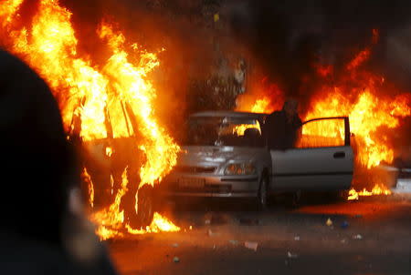 A man tries to save his car set on fire by protesters during a rally against Expo 2015 in Milan, May 1, 2015. REUTERS/Stefano Rellandini