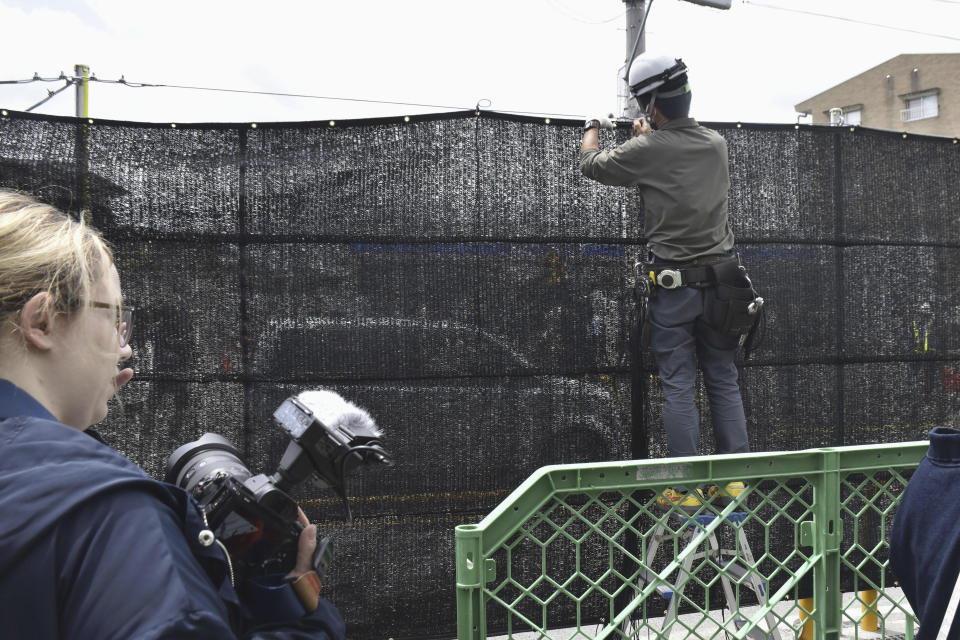 A worker sets up a huge black screen on a stretch of sidewalk at Fujikawaguchiko town, Yamanashi prefecture, central Japan Tuesday, May 21, 2024. Just a few weeks ago, the town began setting up a huge black screen to block a view of Mount Fuji because tourists were crowding into the area to take photos with the mountain as a backdrop to a convenience store, a social media phenomenon known as “Mount Fuji Lawson” that has disrupted business, traffic and local life. (Kyodo News via AP)