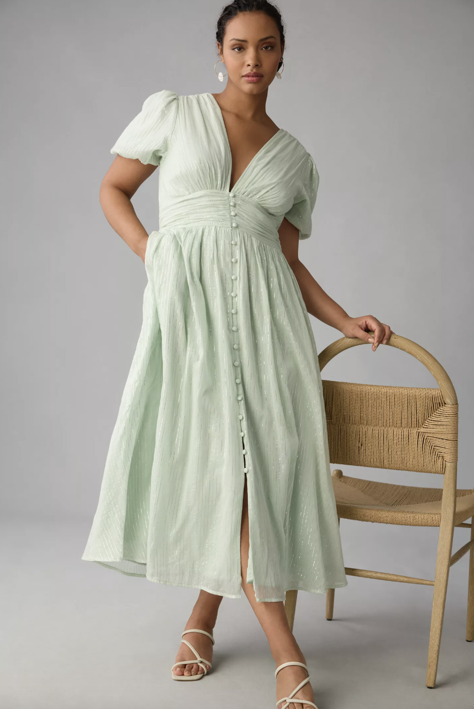 model leaning on chair in light green wedding guest dress, The Catalina Lurex Button-Front Dress (photo via Anthropologie)