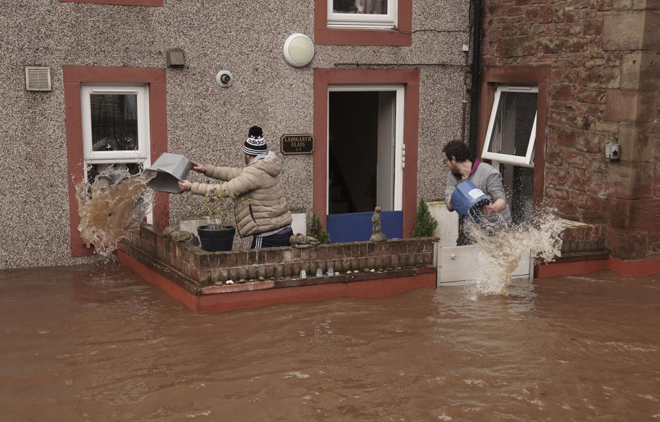 Men try to control the flow of flood water, outside a property, in Appleby-in-Westmorland, as Storm Ciara hits the UK, in Cumbria, England, Sunday Feb. 9, 2020. Trains, flights and ferries have been cancelled and weather warnings issued across the United Kingdom as a storm with hurricane-force winds up to 80 mph (129 kph) batters the region. (Owen Humphreys/PA via AP)