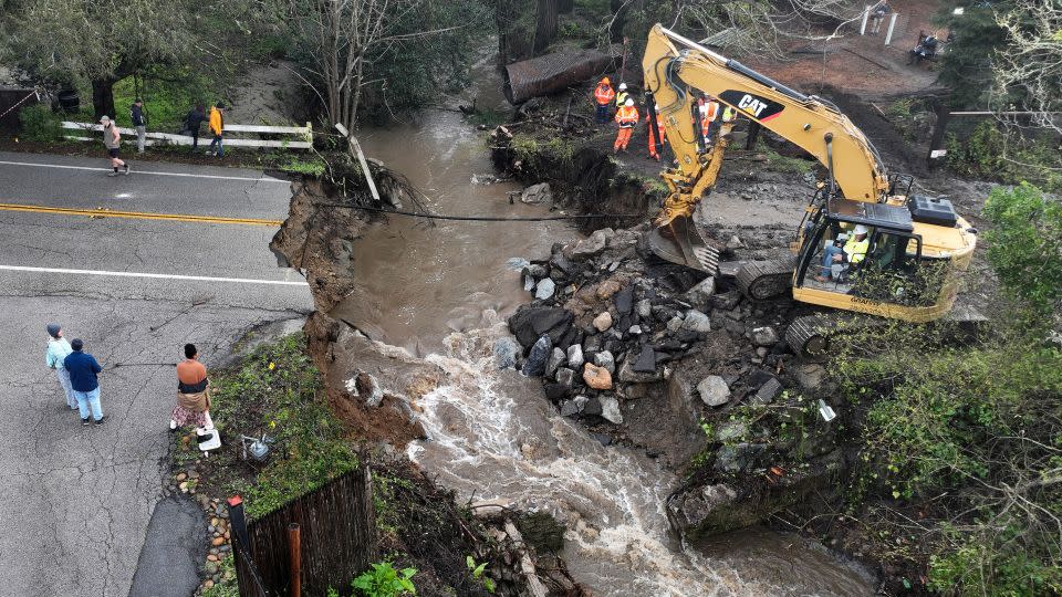 Workers make emergency repairs to a road that was washed out heavy rains on March 10, 2023, in Soquel, California. - Justin Sullivan/Getty Images