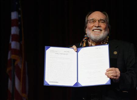 Hawaii Governor Neil Abercrombie holds up Senate Bill 1, allowing same sex marriage to be legal in the state, after signing it in Honolulu, Hawaii November 13, 2013. REUTERS/Hugh Gentry