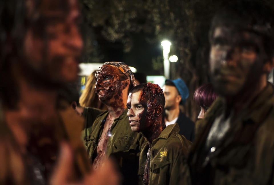 Israelis dressed as a zombies takes part in the customary 'Zombie Walk' in the city of Tel Aviv, on the eve of the Jewish holiday of Purim, late on March 15, 2014. The carnival-like Purim holiday is celebrated with parades and costume parties to commemorate the deliverance of the Jewish people from a plot to exterminate them in the ancient Persian empire 2,500 years ago, as described in the Book of Esther. AFP PHOTO/DAVID BUIMOVITCH        (Photo credit should read DAVID BUIMOVITCH/AFP/Getty Images)