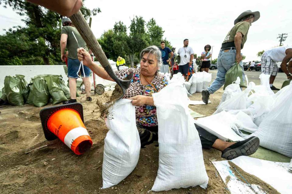 Woman sitting down filling sandbags outdoors