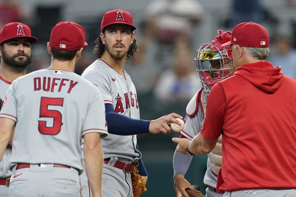 Los Angeles Angels starting pitcher Michael Lorenzen, center, turns the ball over to interim manager Phil Nevin, right, as Matt Duffy (5), Mike Ford, left raer, and Kurt Suzuki right raer, stand by in the sixth inning of a baseball game against the Texas Rangers in Arlington, Texas, Thursday, Sept. 22, 2022. (AP Photo/Tony Gutierrez)