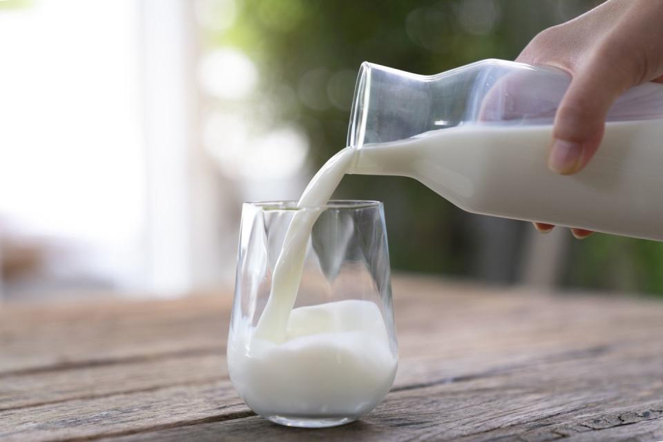 the milk is poured into a ceramic jug into a glass on a natural background