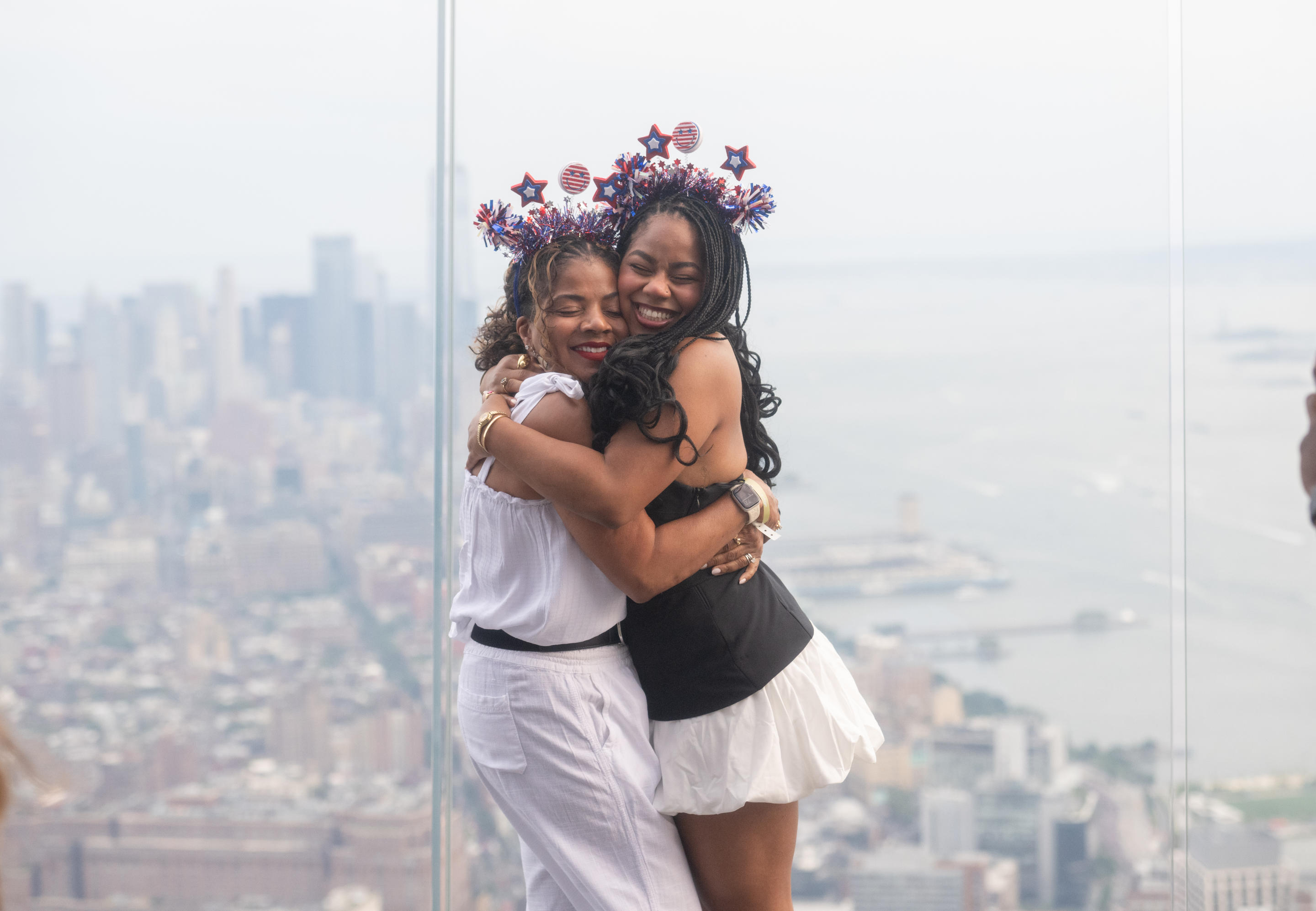 Women embracing and wearing Fourth of July headbands on the observation deck of the Edge.