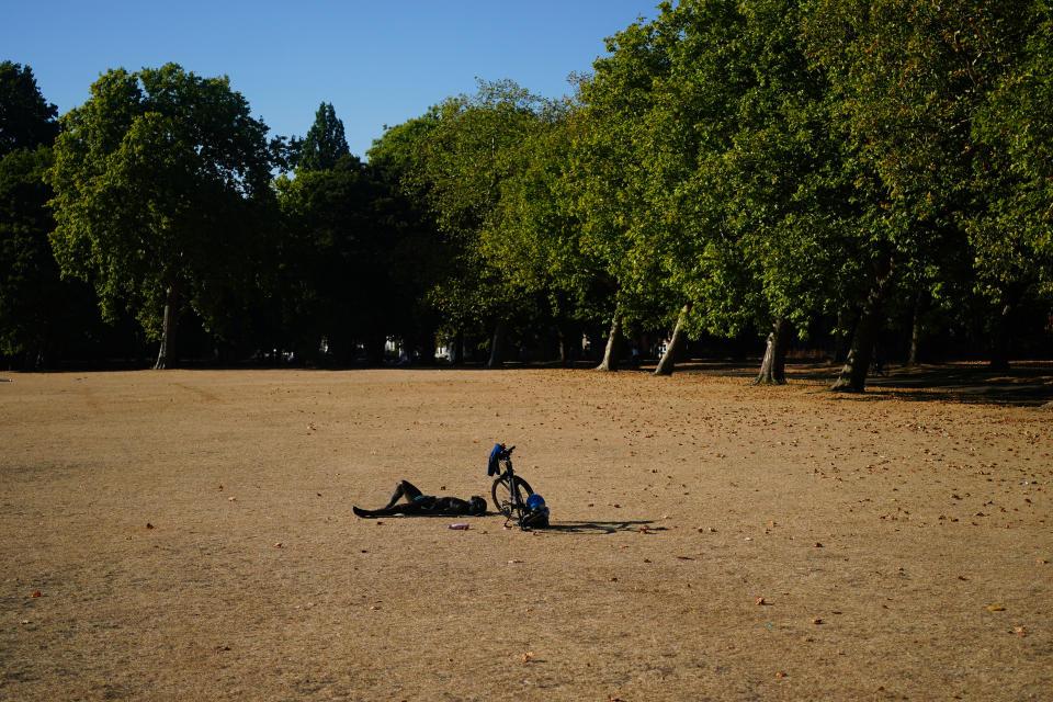 A person lying on dead grass in Victoria Park earlier this month. (PA)