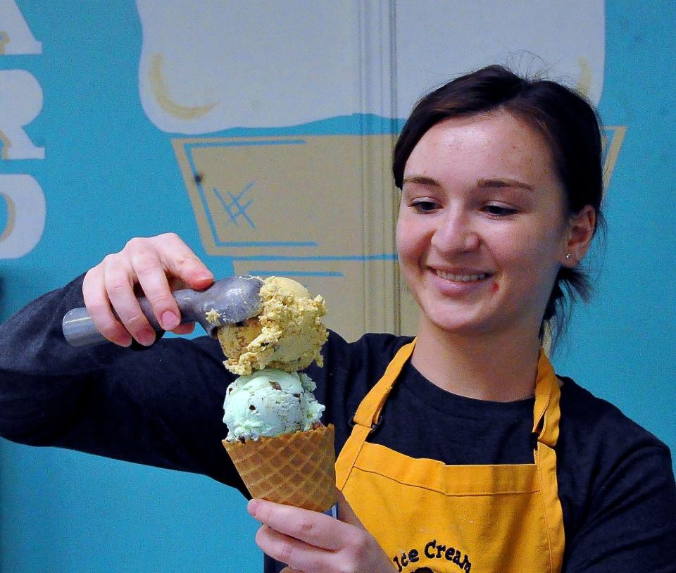 Olivia Nabratil of Hartzler's Dairy of Wooster dips a heifer tracks, mint chip and black raspberry waffle cone.