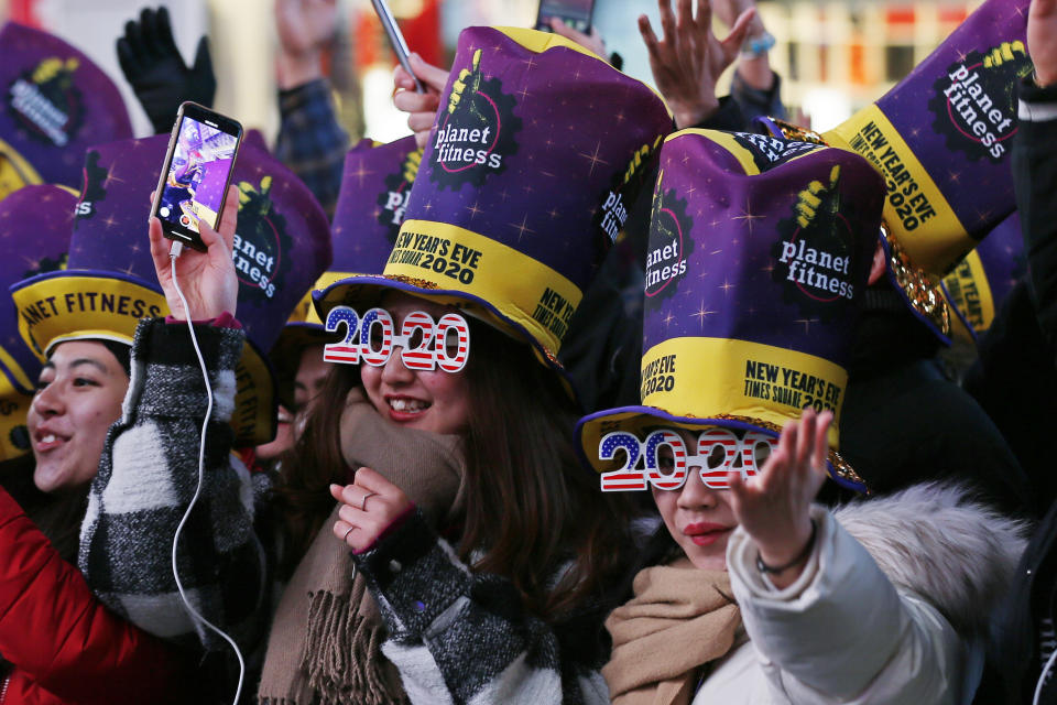 FILE - In this Dec. 31, 2019, file photo, revelers cheer as they wait in New York's Times Square to take part in a New Year's Eve celebration. If ever a year's end seemed like cause for celebration, 2020 might be it. Yet the coronavirus scourge that dominated the year is also looming over New Year's festivities and forcing officials worldwide to tone them down. (AP Photo/Adam Hunger, File)