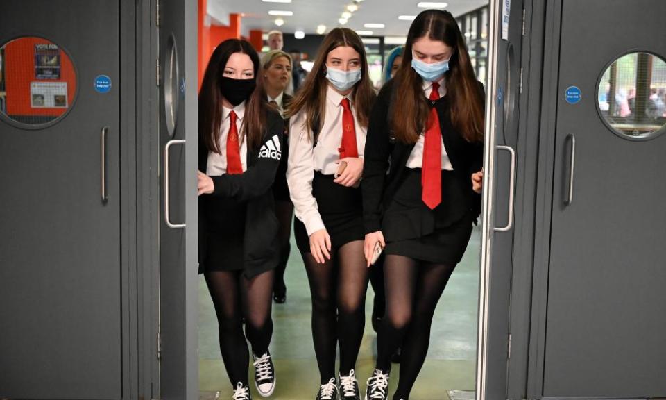 Three girls with masks going through school doors