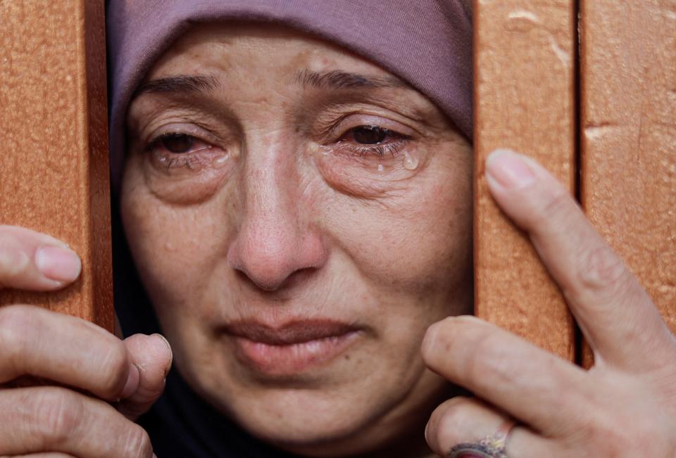 A woman mourns behind a gate next to the bodies of those killed in Israeli airstrikes (REUTERS)