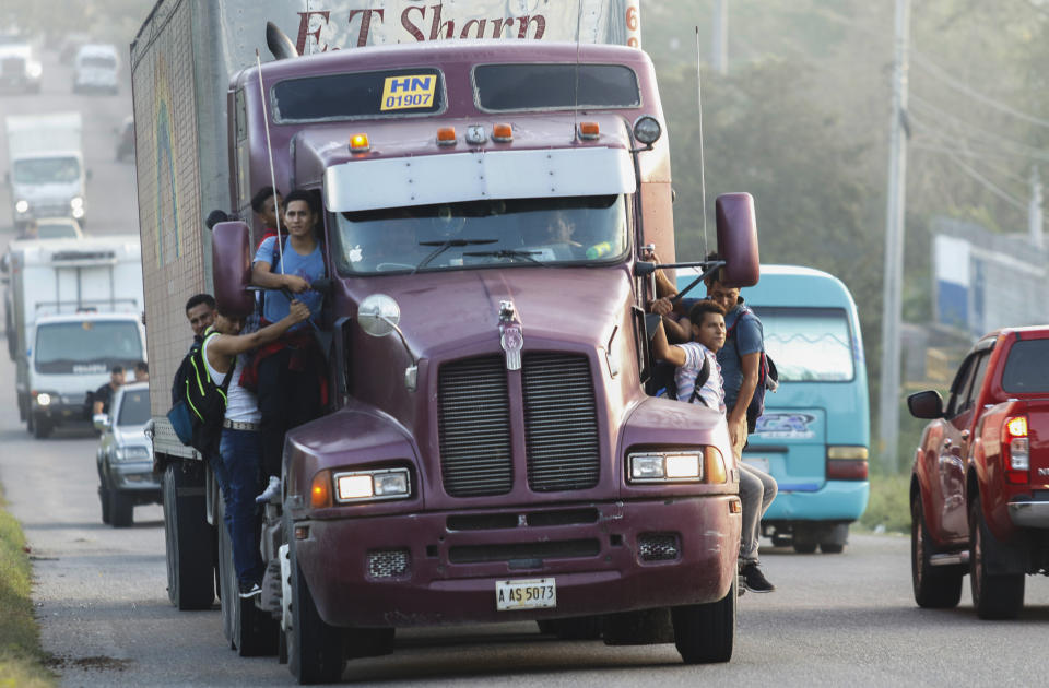 Migrants ride on the side of a truck moving along the highway, in hopes of reaching the distant United States, in San Pedro Sula, Honduras, early Wednesday, Jan. 15, 2020. Hundreds of Honduran migrants started walking and hitching rides Wednesday from the city of San Pedro Sula, in a bid to form the kind of migrant caravan that reached the U.S. border in 2018. (AP Photo/Delmer Martinez)