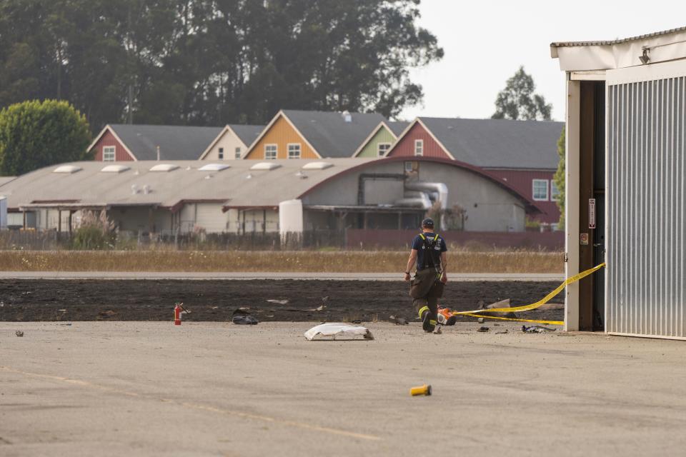 A firefighter walks by wreckage from a plane crash at Watsonville Municipal Airport in Watsonville, Calif., Thursday, Aug. 18, 2022.