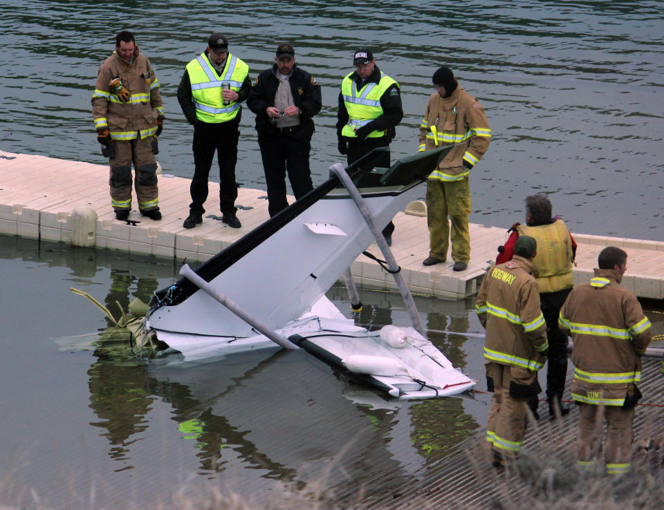 This photo provided by the Ouray County Plaindealer shows rescue personnel examining the tail second of a plane on Saturday, March 22, 2014 after it was recovered from the Ridgeway Reservoir south of Montrose. Colo. The plane believed to be carrying five people crashed into a reservoir in southwestern Colorado and authorities say all are feared dead. Divers are to be used Sunday to search for victims and to recover the rest of the plane. (AP Photo/Ouray County Plaindealer, Patrick Moore) MANDATORY CREDIT