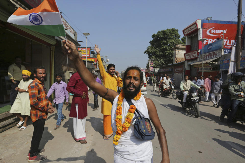 A Hindu devotee waves an Indian national flag and celebrates a verdict in a decades-old land title dispute between Muslims and Hindus, in Ayodhya, India , Saturday, Nov. 9, 2019. India's Supreme Court on Saturday ruled in favor of a Hindu temple on a disputed religious ground and ordered that alternative land be given to Muslims to build a mosque. The dispute over land ownership has been one of the country's most contentious issues. (AP Photo/Rajesh Kumar Singh)