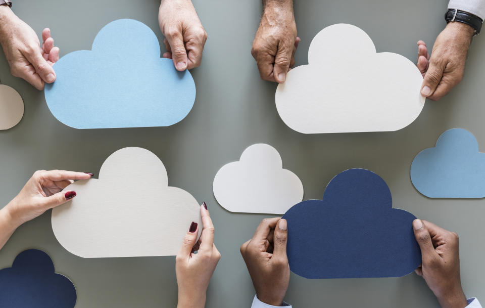 Four people holding cardboard cutouts of clouds.