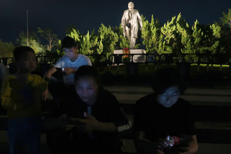 People sit on steps in front of the statue of the former Chinese leader Deng Xiaoping ahead of the 40th anniversary of China's reform and opening up in Shenzhen, Guangdong province, China December 4, 2018.