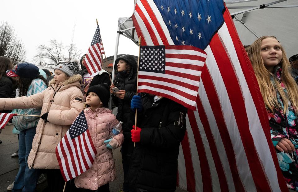 Feb 22, 2023; East Palestine, Ohio, USA; Layne Gruber, 8, of East Palestine holds a flag while waiting out the rain in a group waiting to see former President Donald Trump arrive in a motorcade. Mandatory Credit: Brooke LaValley/Columbus Dispatch