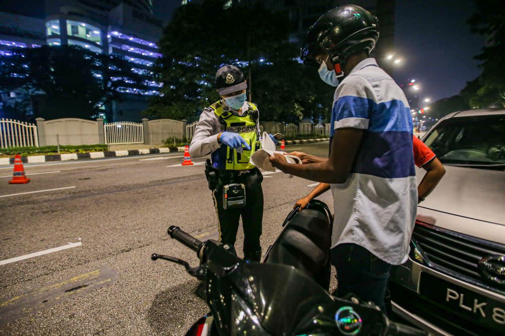 Traffic police personnel conduct checks on motorists during a roadblock on Jalan Raja Laut in Kuala Lumpur May 30, 2020. — Picture by Hari Anggara