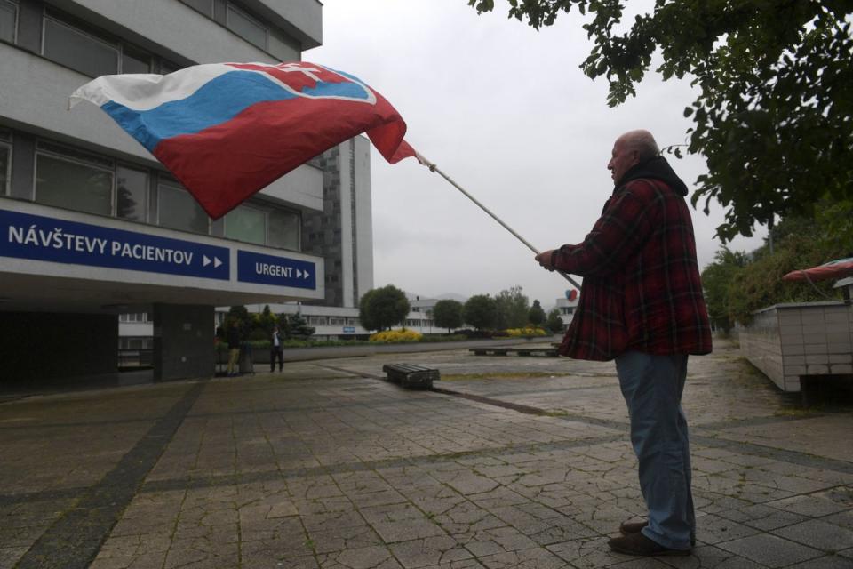 A man waves the Slovakian flag outside the hospital in Banska Bystrica where Mr Fico is being treated (AFP via Getty Images)
