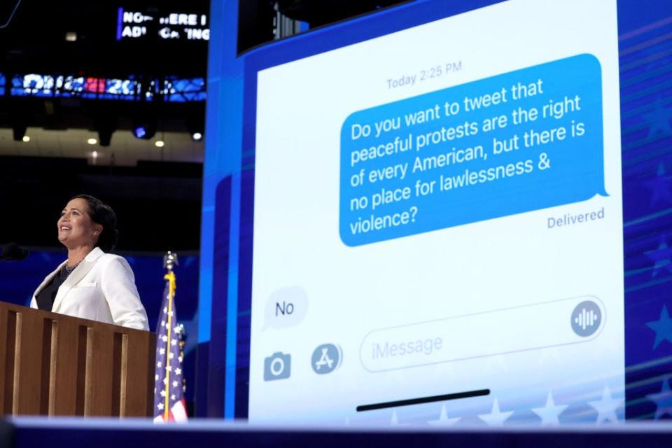 Stephanie Grisham speaks at the DNC. Behind her, a screen shows a text exchange between Melania Trump and Grisham.