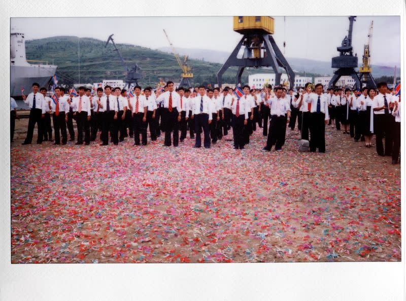 FILE PHOTO: Local residents wave as a cruise ship with visitors leaves the port in the North Korean special economic zone of Rason