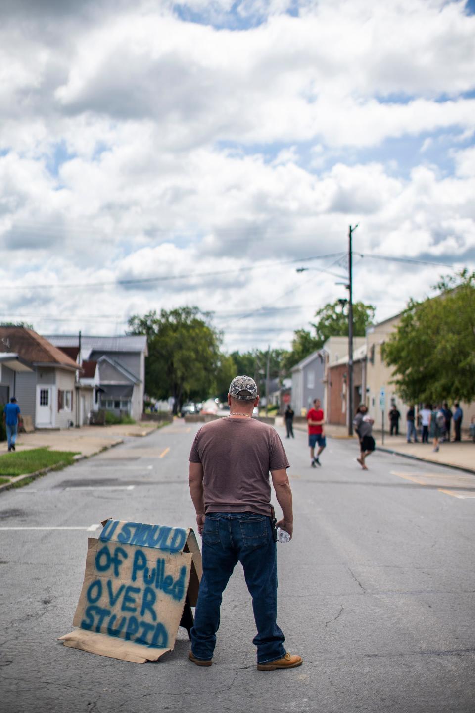 A local man, who refused to give his name, stands next to several hostile signs Saturday near a protest outside the Circleville Police Department in reaction to officer Ryan Speakman releasing his K-9 on an unarmed truck driver July 4. Only a handful of protesters showed up, and about twice as many locals came to watch.