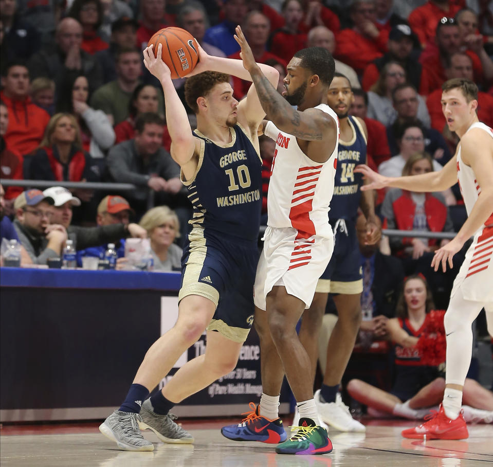 George Washington's Jamison Battie (10) is defended by Dayton's Trey Landers (3) during the first half of an NCAA college basketball game Saturday, March 7, 2020, in Dayton, Ohio. (AP Photo/Tony Tribble)