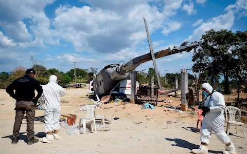 Technicians work at the site of the accident where a military helicopter fell on a van - Credit: ALFREDO ESTRELLA/AFP/Getty Images