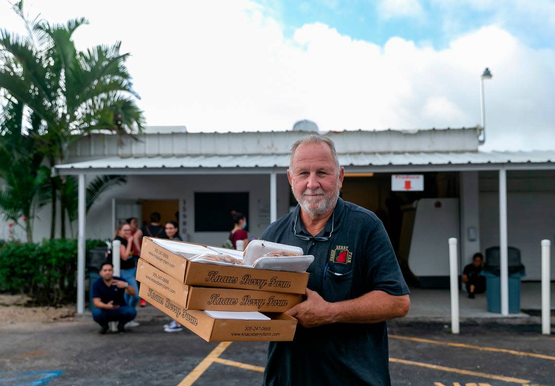 Herb Grafe, who has been working at Knaus Berry Farm for almost 47 years, helps load a customer’s vehicle with freshly baked cinnamon rolls and other goods during their opening day in Homestead, Florida, on Tuesday, Oct. 26, 2021.