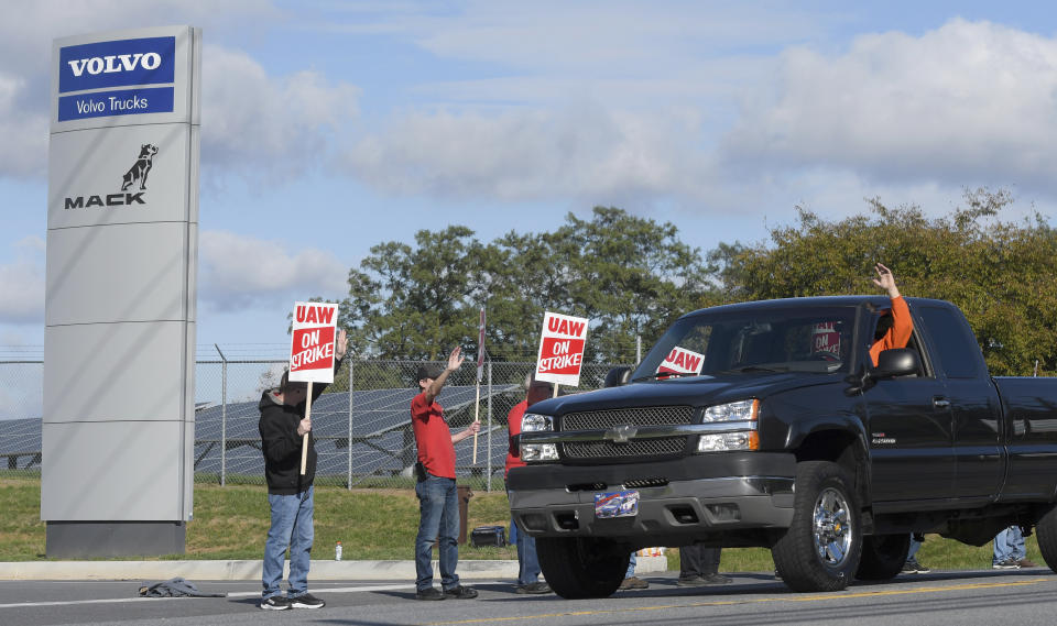 A motorist waves to members of UAW Local 171 as they picket outside a Mack Trucks facility in Hagerstown, Md. after going on strike Monday, Oct. 9, 2023. Workers voted down a tentative five-year contract agreement that negotiators had reached with the company. (AP Photo/Steve Ruark)