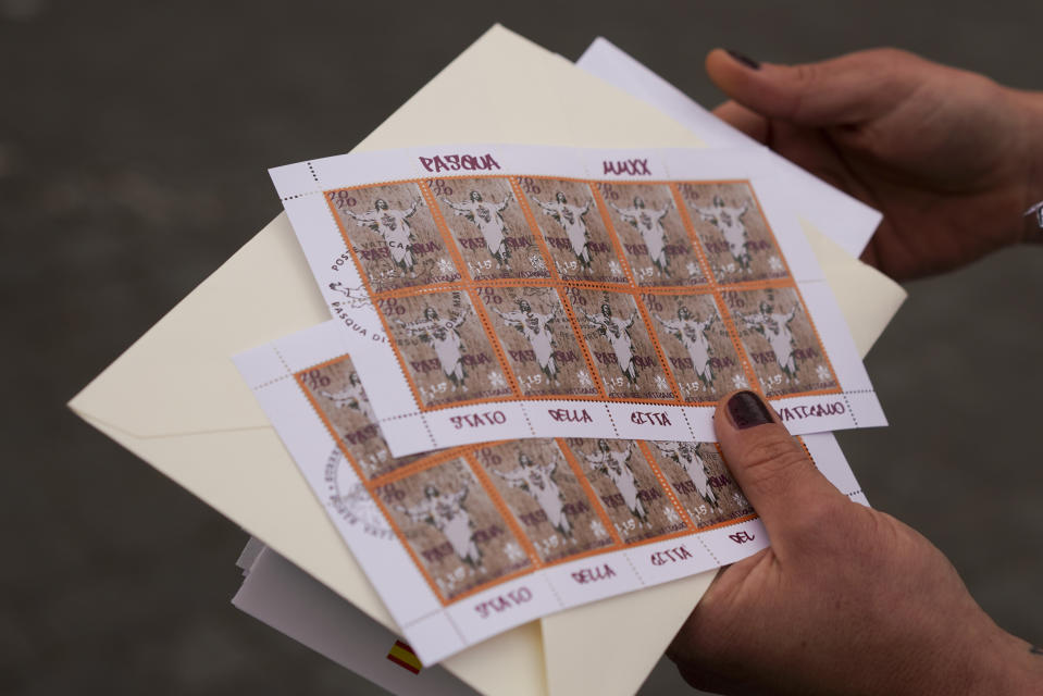 Artist Alessia Babrow shows the Vatican stamps during an interview with the Associated Press, at the Vatican, Friday, May 14, 2021. Babrow sued the Vatican City State’s telecommunications office in a Rome court last month, saying it was wrongfully profiting off her creativity and violating the original intent of her artwork. The lawsuit, which is seeking nearly 130,000 euro in damages, said the Vatican had ignored Babrow’s attempts to negotiate a settlement after she discovered it had reproduced her poster art unlawfully. (AP Photo/Andrew Medichini)