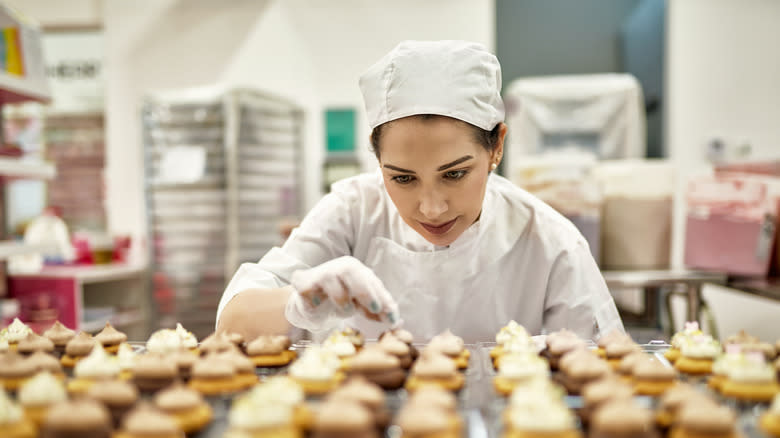 A chef decorating cupcakes