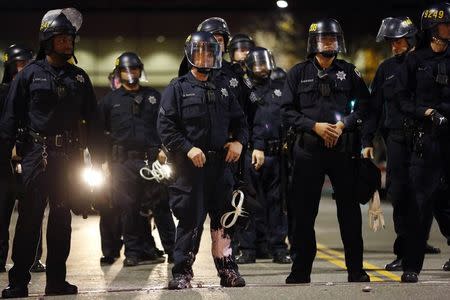 A police officer looks into the crowd, after he was hit on the leg with paint thrown by protesters during an evening demonstration against police violence, in Oakland, California December 13, 2014. REUTERS/Stephen Lam