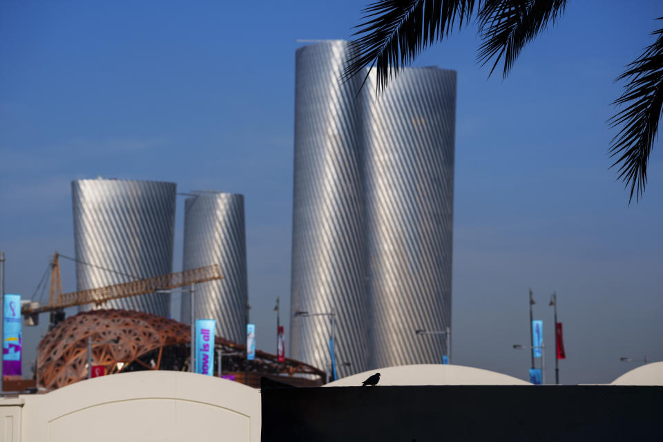 A bird sits on a fence with the Lusail plaza towers in the background in Lusail downtown, Qatar, Thursday, Nov. 24, 2022. (AP Photo/Pavel Golovkin)