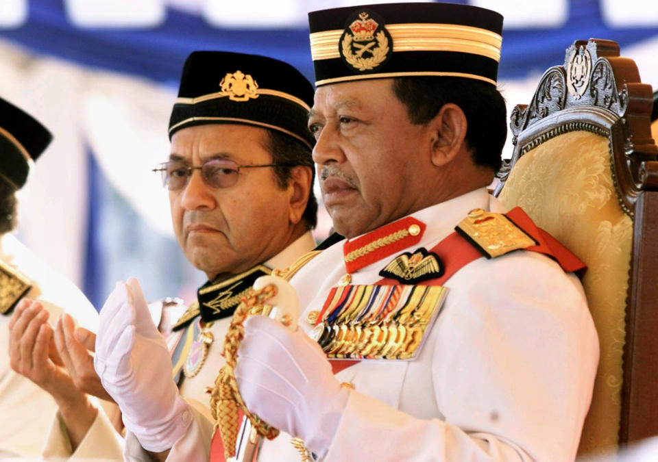 FILE - In this June 1, 2002, file photo, then Malaysian King Syed Sirajuddin Syed Putra Jamalullail, right, and Malaysia's Prime Minister Mahathir Mohamad, left, pray during the Trouping the Colors in conjunction with Malaysia King's official birthday anniversary at the Independence Square in Kuala Lumpur, Malaysia. Sultan Muhammad V shocked the nation by announcing his abdication in January 2019, days after returning from two months of medical leave. The 49-year-old sultan from eastern Kelantan state only reigned for two years as Malaysia's 15th king and didn't give any reason for quitting. (AP Photo/TehEng Koon, File)